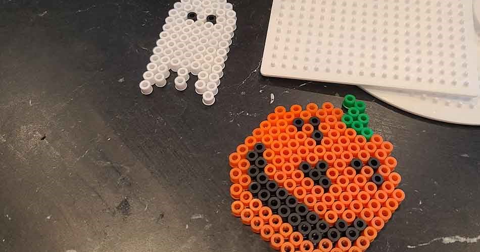 Halloween-motiver laget av perler med gresskar og spøkelser på perleplater.