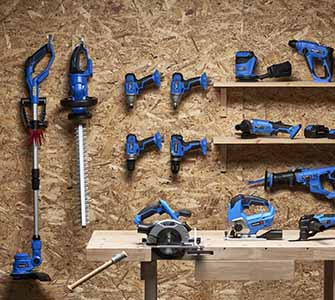 Garden tools and machinery hung organized on a wall in a storage room.