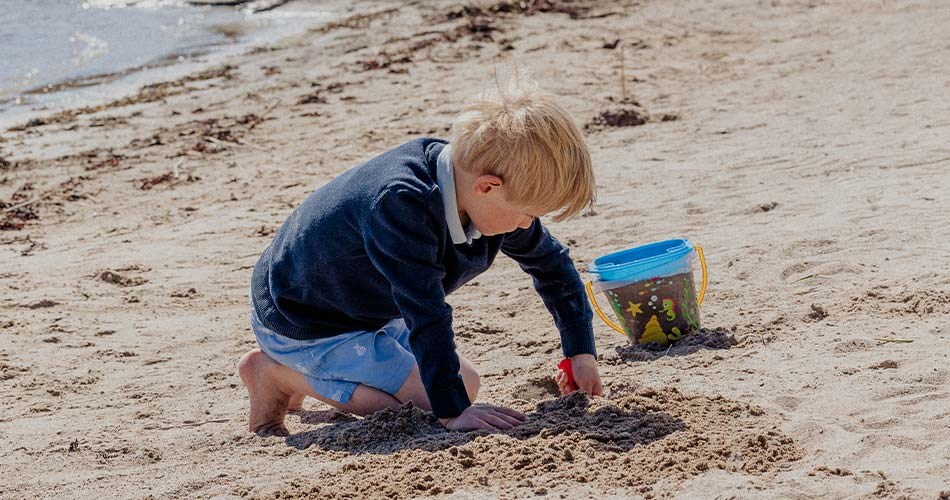 En gutt leker med strandleksaker på en strand.